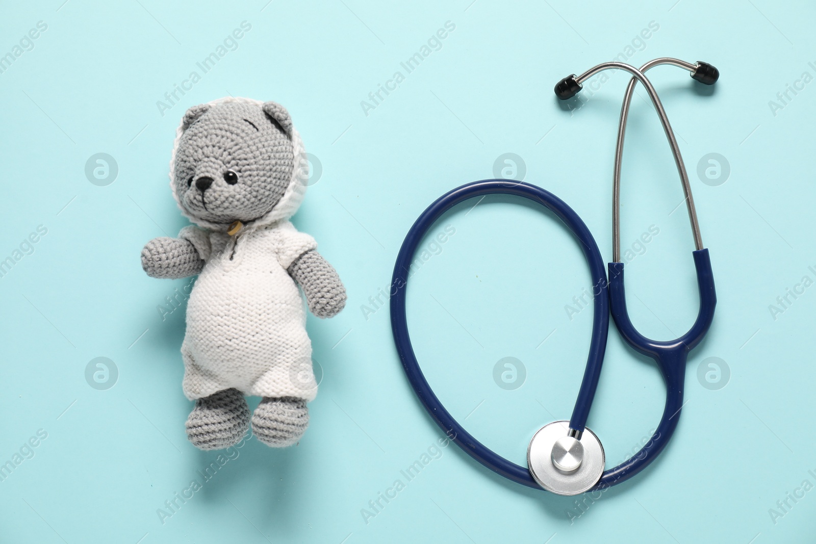 Photo of Pediatrics concept. Toy bear with stethoscope on light blue background, top view