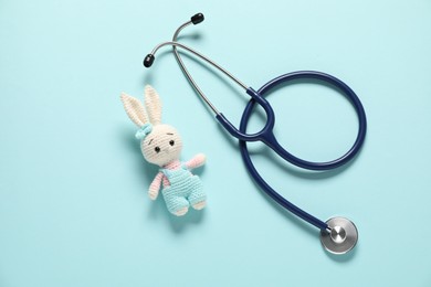 Photo of Pediatrics concept. Toy bunny with stethoscope on light blue background, top view