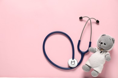 Photo of Pediatrics concept. Toy bear with stethoscope on pink background, top view. Space for text