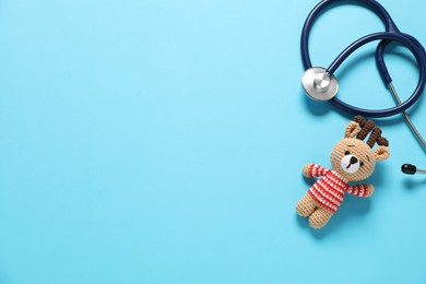 Photo of Pediatrics concept. Toy deer with stethoscope on light blue background, top view. Space for text