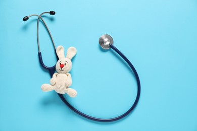 Photo of Pediatrics concept. Toy bunny with stethoscope on light blue background, top view