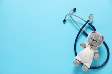 Photo of Pediatrics concept. Toy bear with stethoscope on light blue background, top view. Space for text