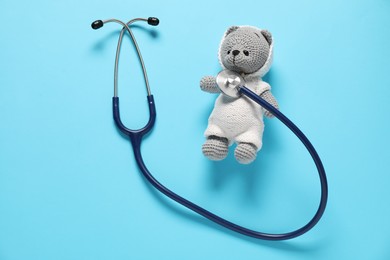 Photo of Pediatrics concept. Toy bear with stethoscope on light blue background, top view