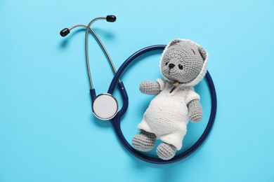 Photo of Pediatrics concept. Toy bear with stethoscope on light blue background, top view