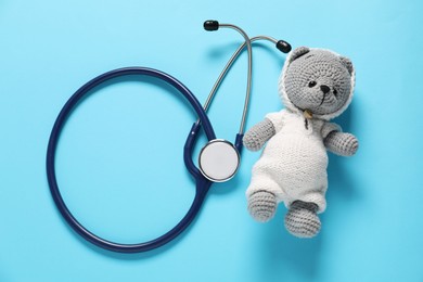 Photo of Pediatrics concept. Toy bear with stethoscope on light blue background, top view