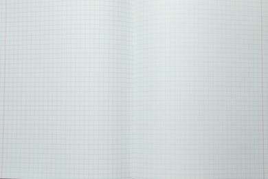 Photo of Open copybook with checkered sheets of paper as background, top view