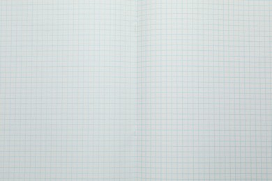 Photo of Open copybook with checkered sheets of paper as background, top view