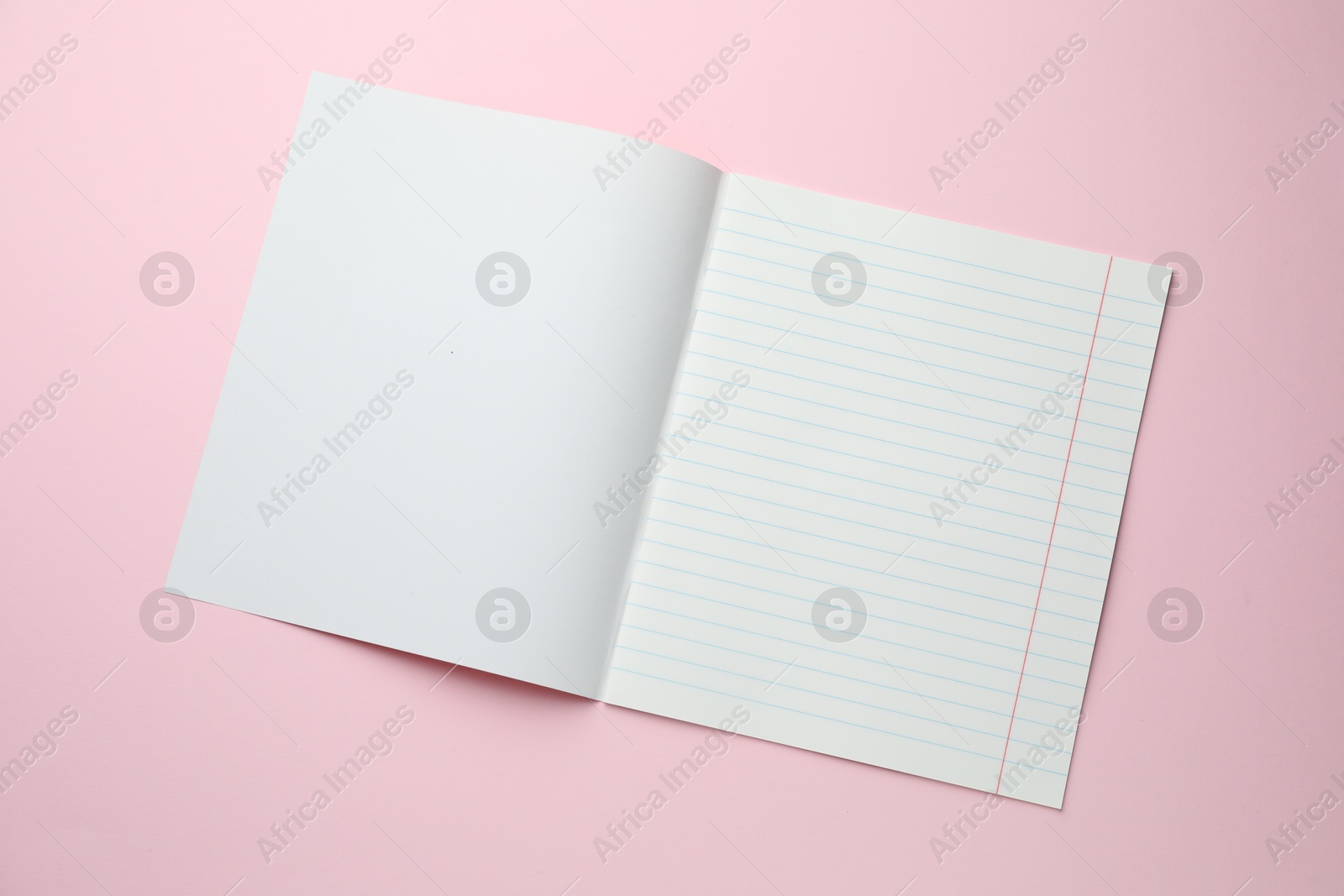 Photo of Open copybook on pink background, top view. School stationery