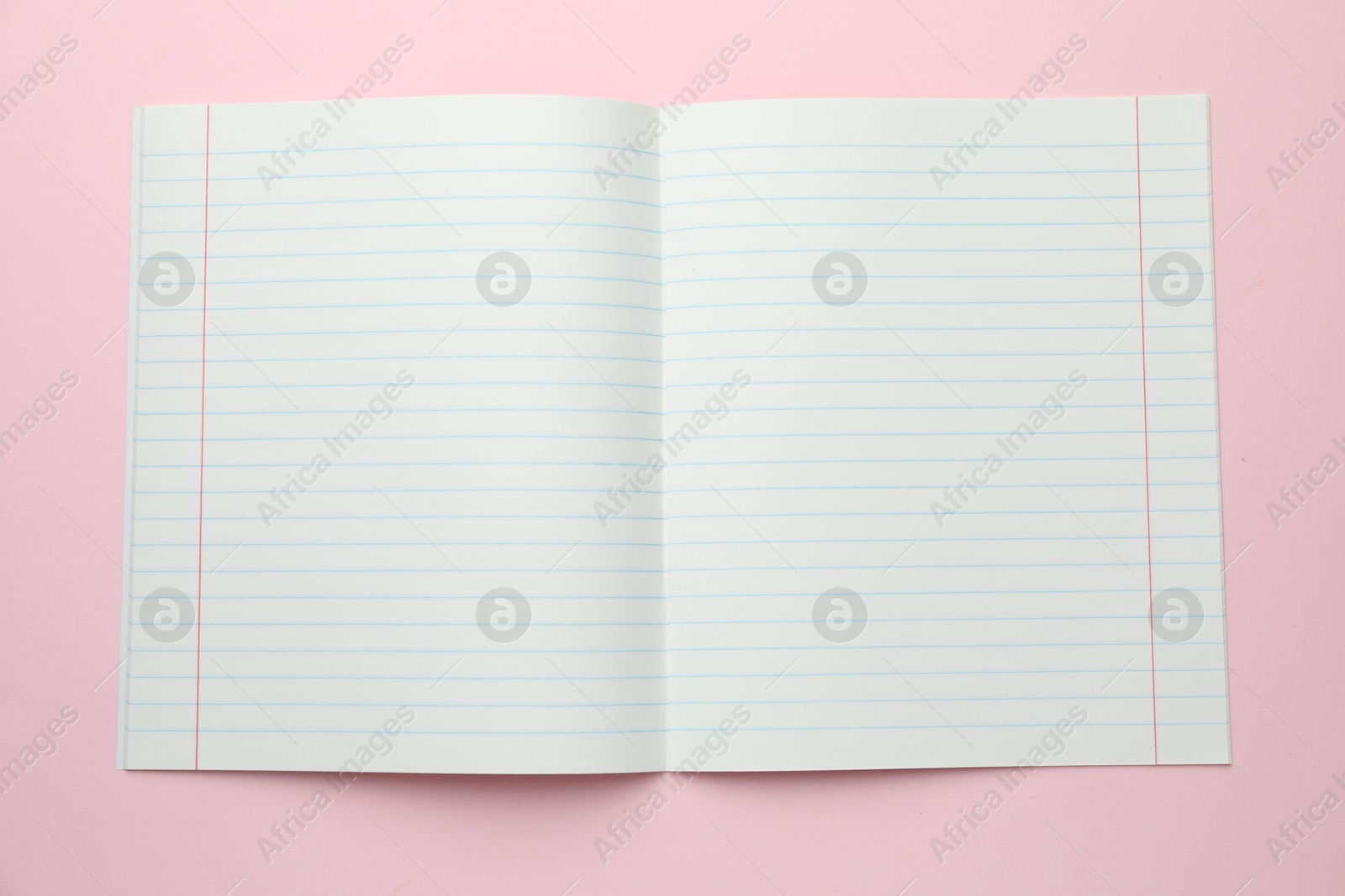 Photo of Open copybook on pink background, top view. School stationery