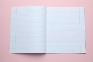 Photo of Open copybook on pink background, top view. School stationery