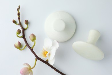 Spa stones and orchid branch on white background, flat lay