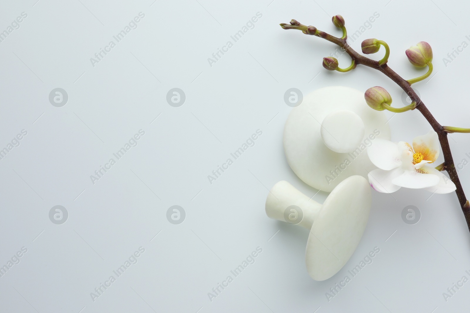 Photo of Spa stones and orchid branch on white background, flat lay. Space for text