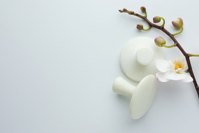 Photo of Spa stones and orchid branch on white background, flat lay. Space for text