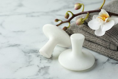 Spa stones, orchid branch and towels on white marble table, closeup. Space for text