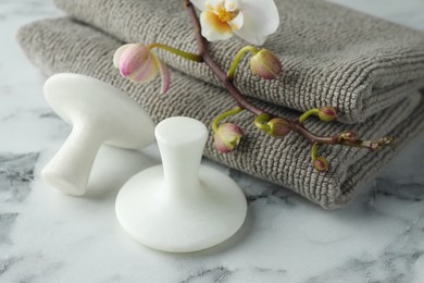 Photo of Spa stones, orchid branch and towels on white marble table, closeup