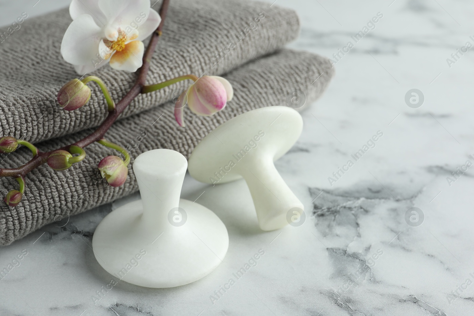 Photo of Spa stones, orchid branch and towels on white marble table, closeup. Space for text