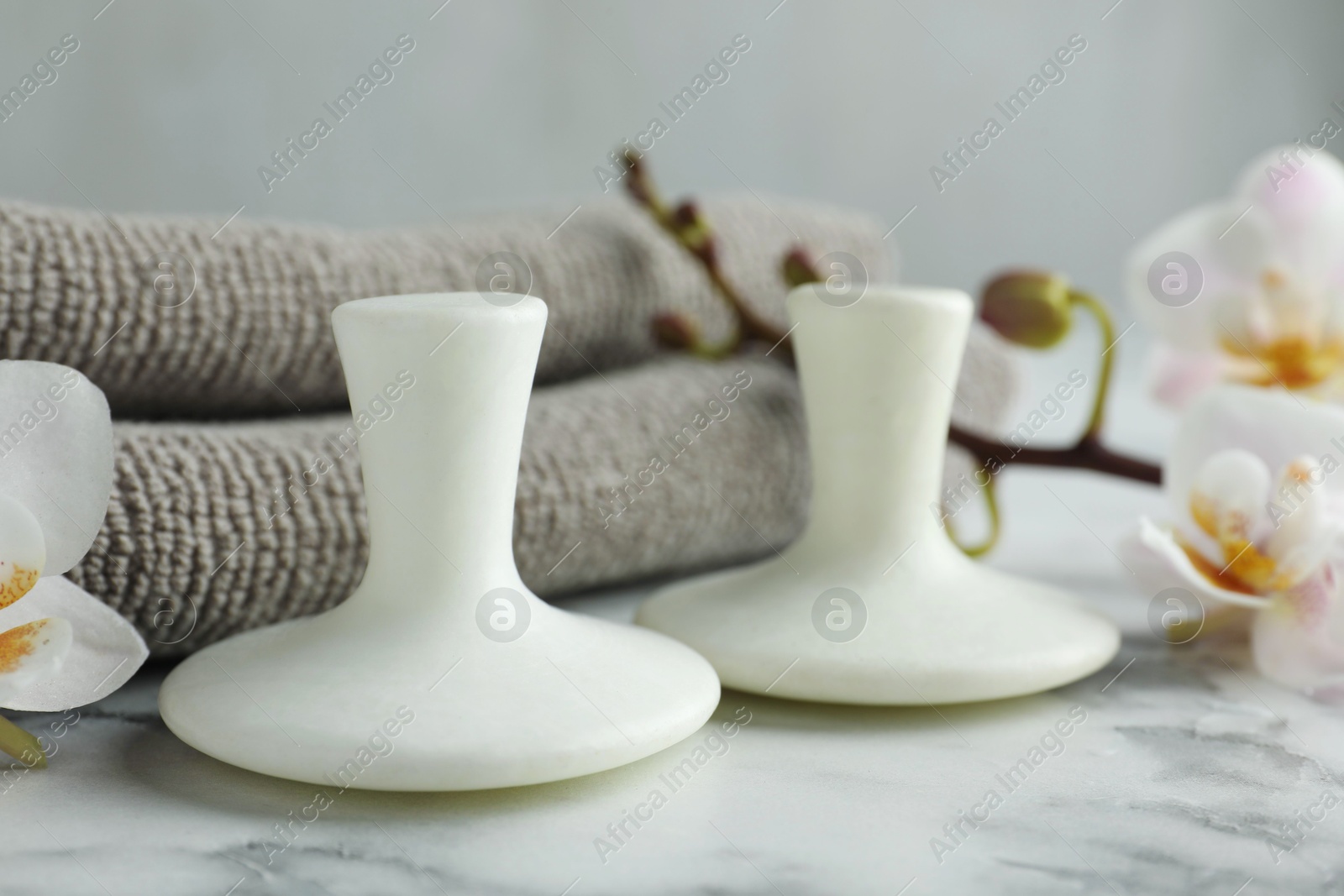 Photo of Spa stones, orchid flowers and towels on white marble table, closeup