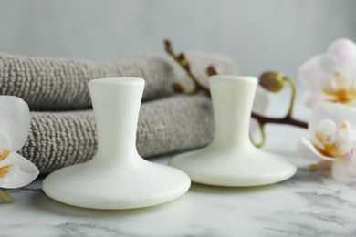 Spa stones, orchid flowers and towels on white marble table, closeup