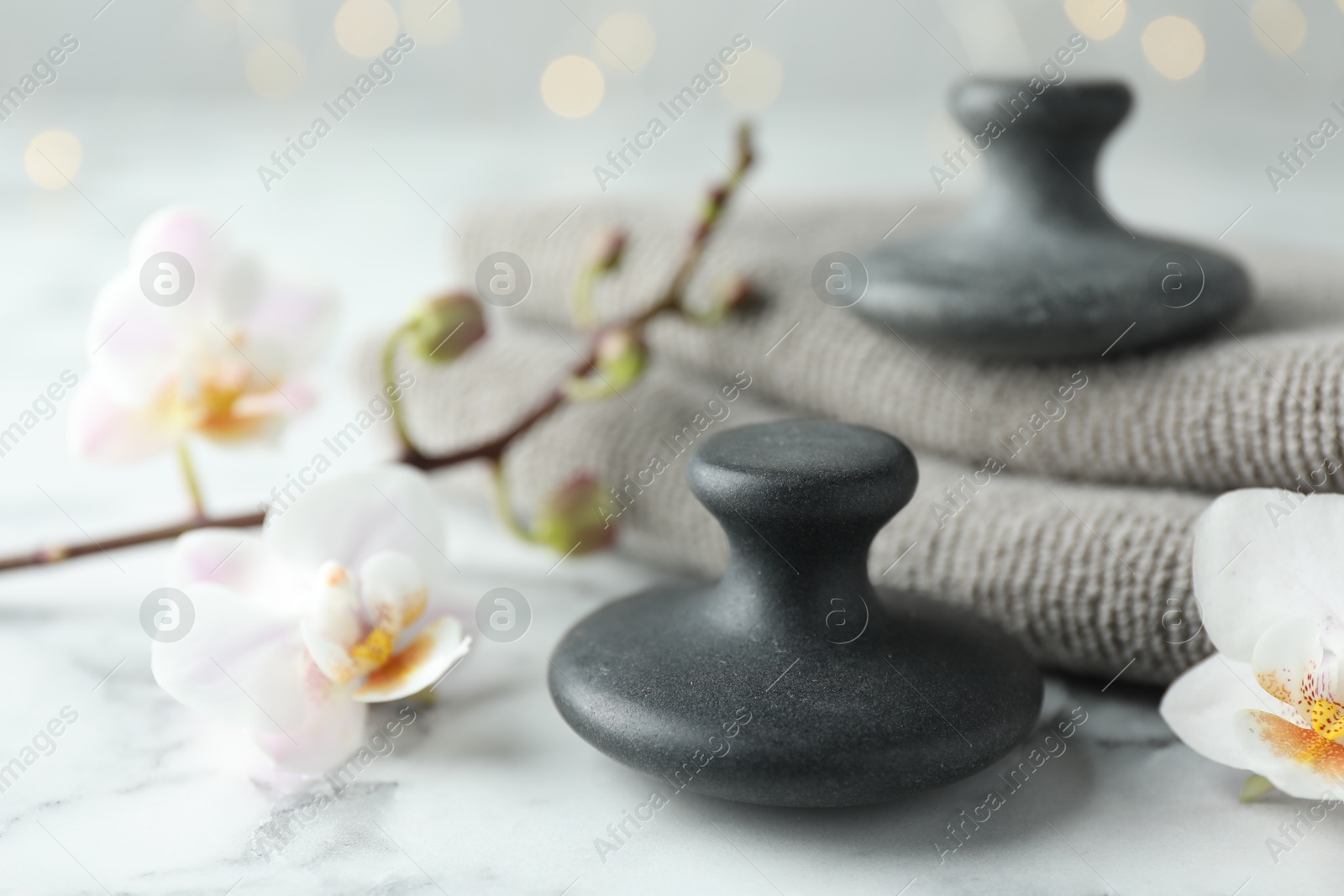 Photo of Spa stones, orchid flowers and towels on white marble table, closeup