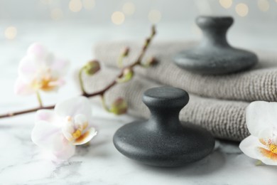 Photo of Spa stones, orchid flowers and towels on white marble table, closeup