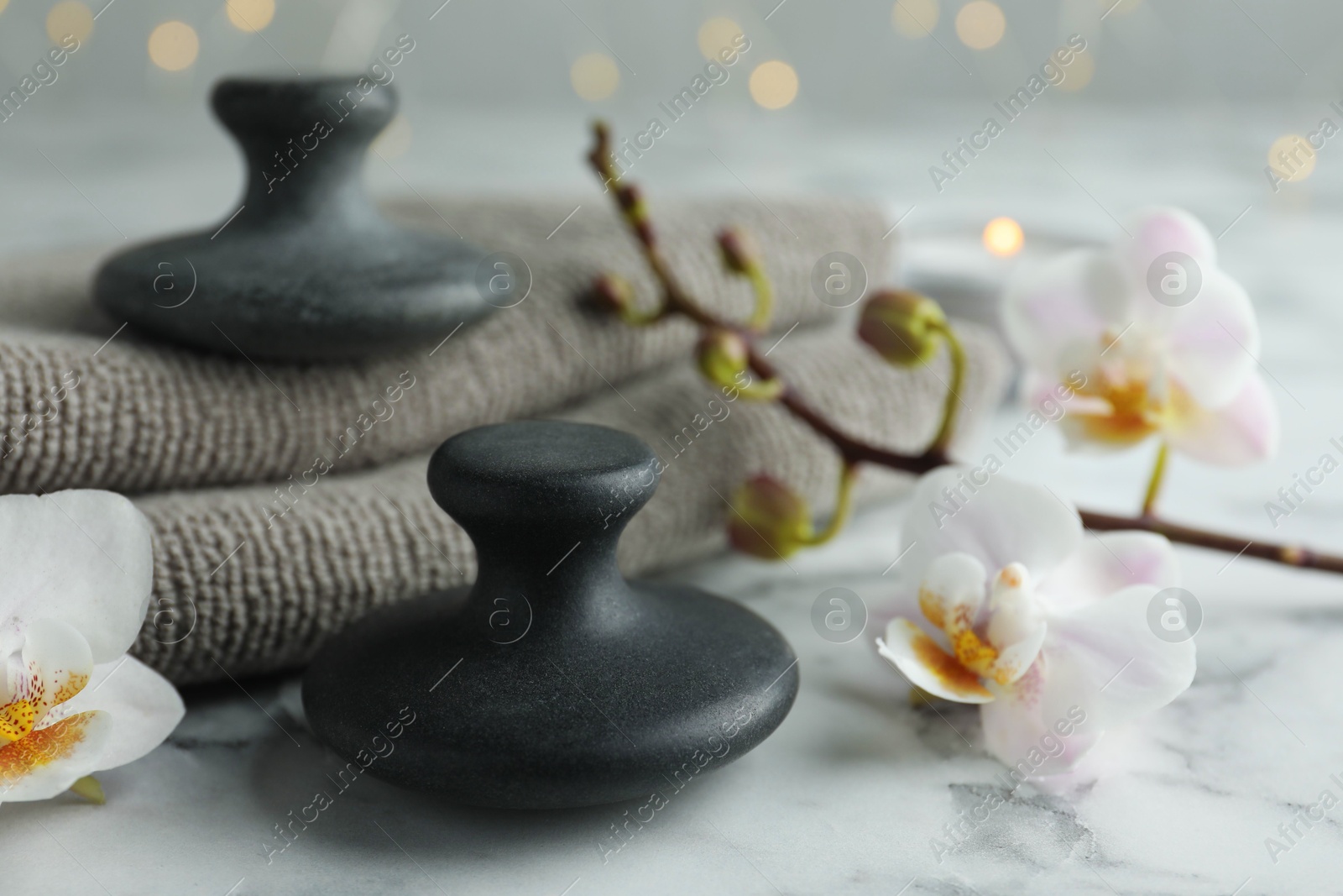 Photo of Spa stones, orchid flowers and towels on white marble table, closeup