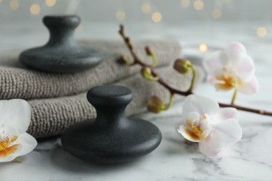 Spa stones, orchid flowers and towels on white marble table, closeup