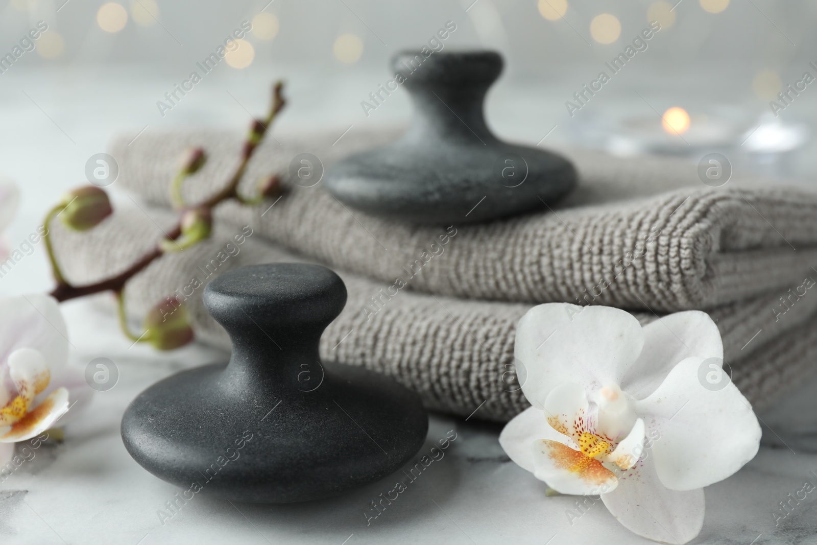 Photo of Spa stones, orchid flowers and towels on white marble table, closeup