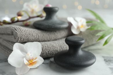 Spa stones, orchid flowers, towels and palm leaf on white marble table, closeup