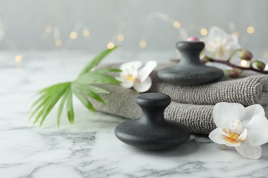 Photo of Spa stones, orchid flowers, towels and palm leaf on white marble table, closeup