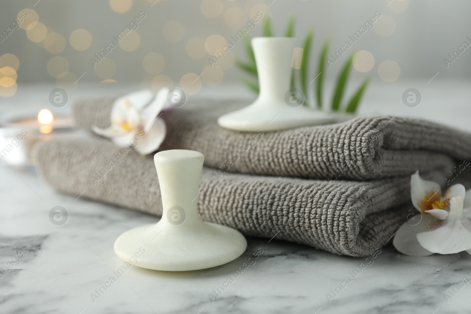 Photo of Spa stones, orchid flowers, towels and leaf on white marble table, closeup