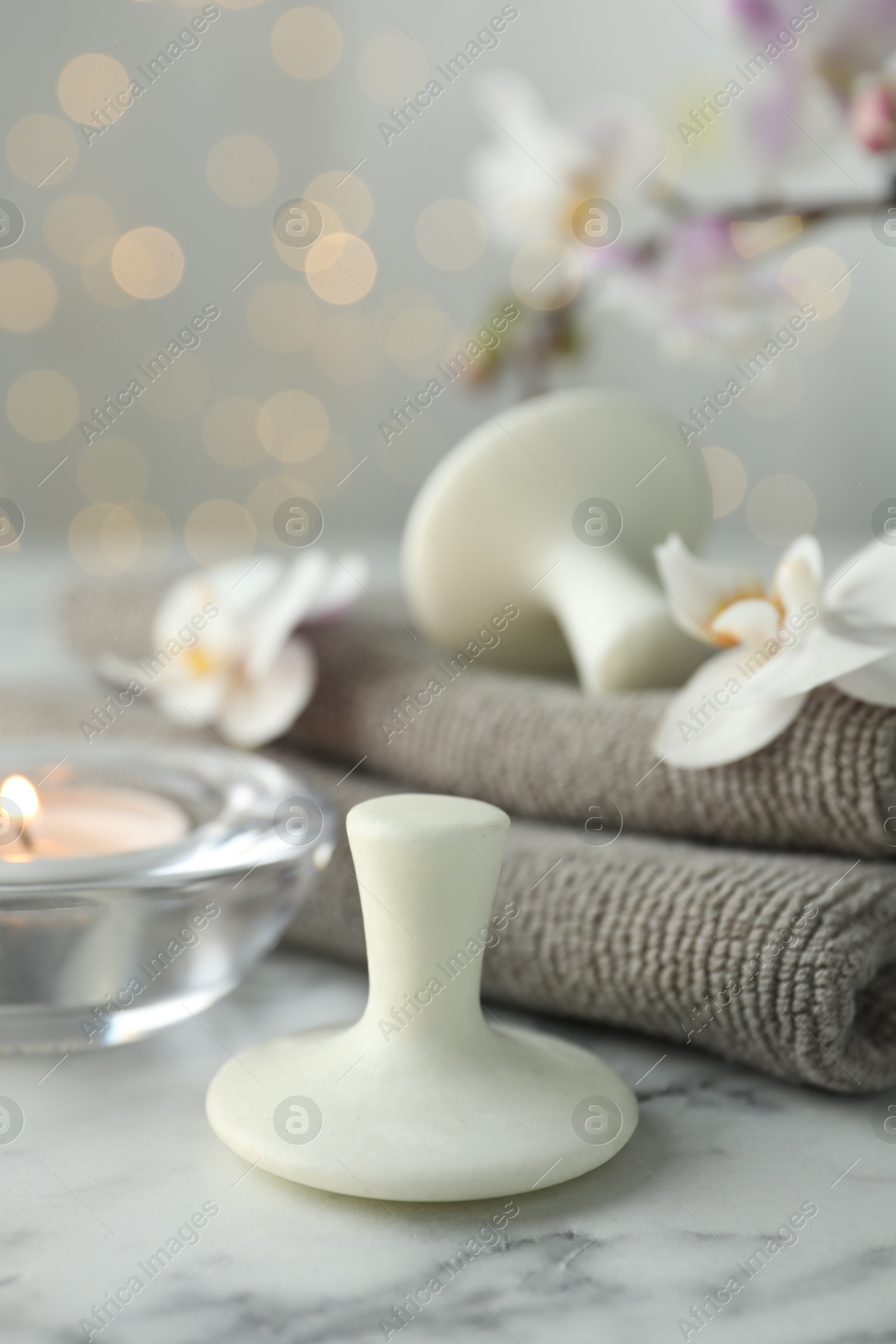 Photo of Spa stones, orchid flowers, towels and burning candle on white marble table, closeup