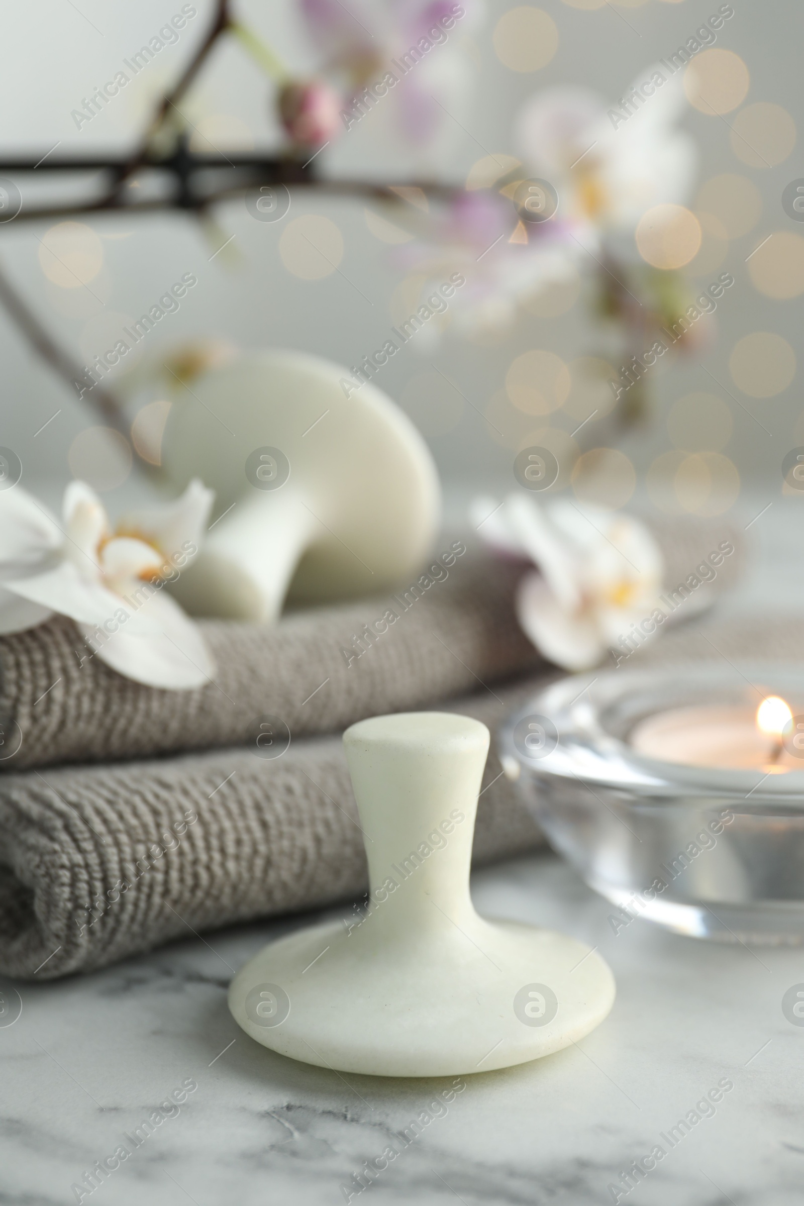 Photo of Spa stones, orchid flowers, towels and burning candle on white marble table, closeup