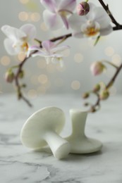 Spa stones on white marble table and orchid branch against blurred lights, closeup