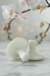 Spa stones on white marble table and orchid branch against blurred lights, closeup