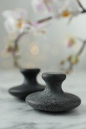 Spa stones on white marble table and orchid branch against blurred lights, closeup