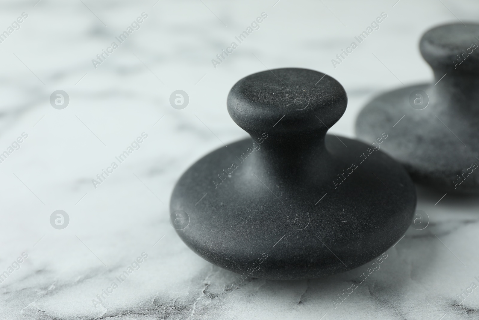 Photo of Spa stones on white marble table, closeup. Space for text