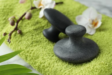 Photo of Spa stones, orchid branch, leaves and towel on table, closeup