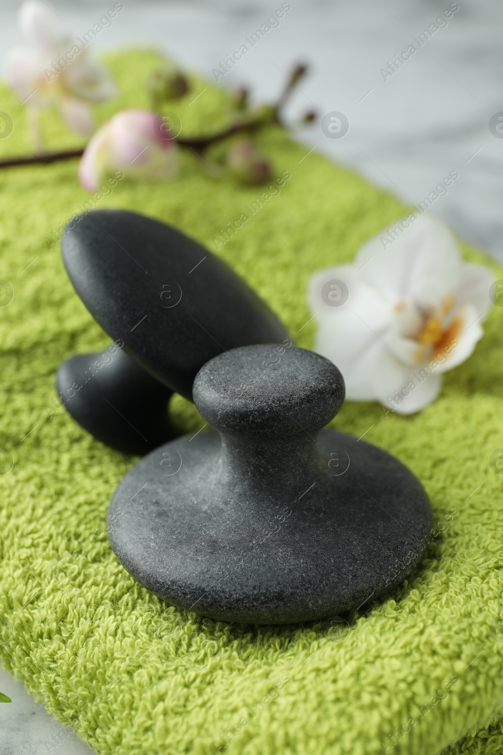 Photo of Spa stones, orchid flower and towel on table, closeup