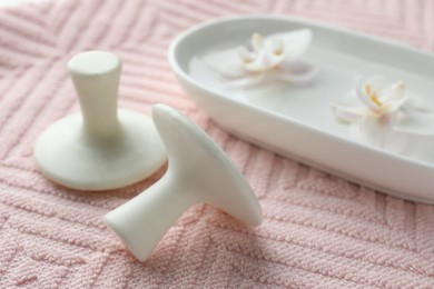 Photo of Spa stones and flowers on pink towel, closeup