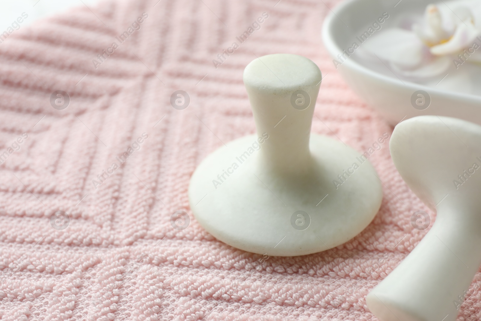 Photo of Spa stones and flower on pink towel, closeup. Space for text