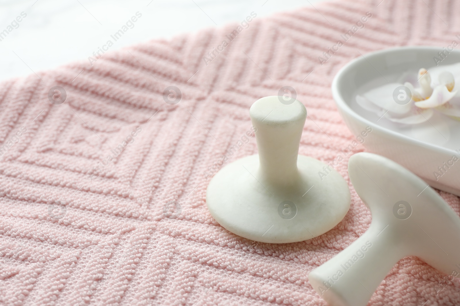 Photo of Spa stones, flower and pink towel on table, closeup. Space for text