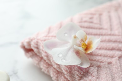 Photo of Orchid flower and towel on white marble table, closeup