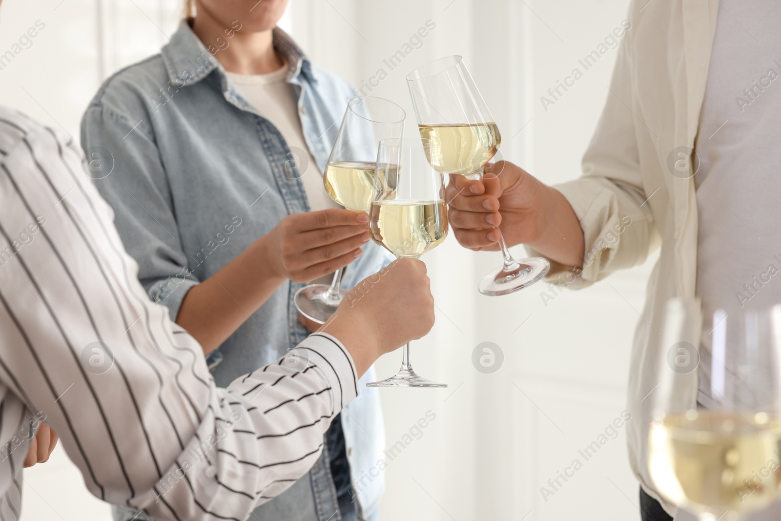 Photo of People clinking glasses of wine indoors, closeup