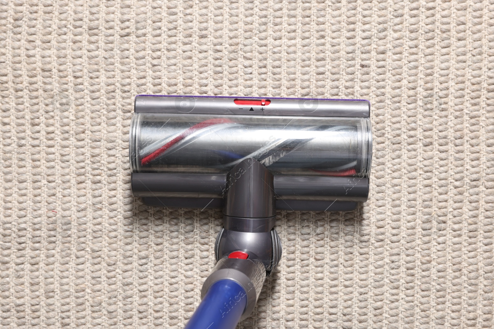 Photo of Cleaning carpet with cordless vacuum cleaner indoors, top view