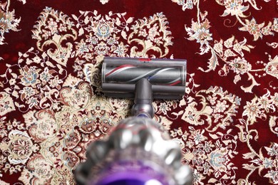 Photo of Cleaning carpet with cordless vacuum cleaner indoors, top view