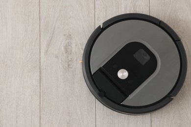 Photo of Robotic vacuum cleaner on wooden floor, top view. Space for text