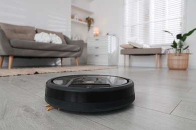 Photo of Robotic vacuum cleaner on wooden floor in living room