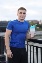 Photo of Athletic man with shaker of protein drink outdoors