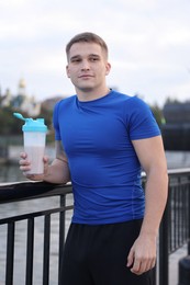 Photo of Athletic man with shaker of protein drink outdoors