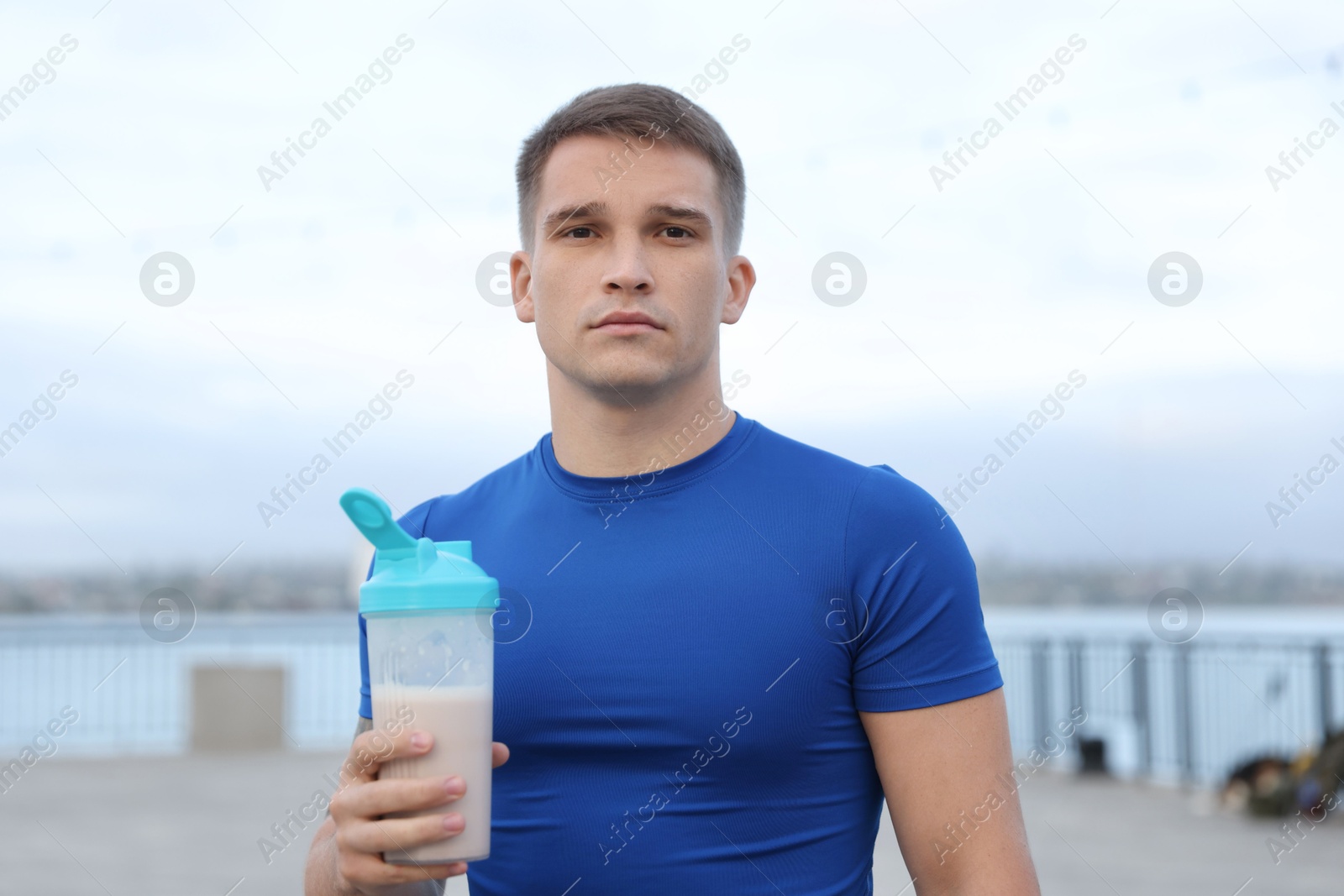 Photo of Athletic man with shaker of protein drink outdoors